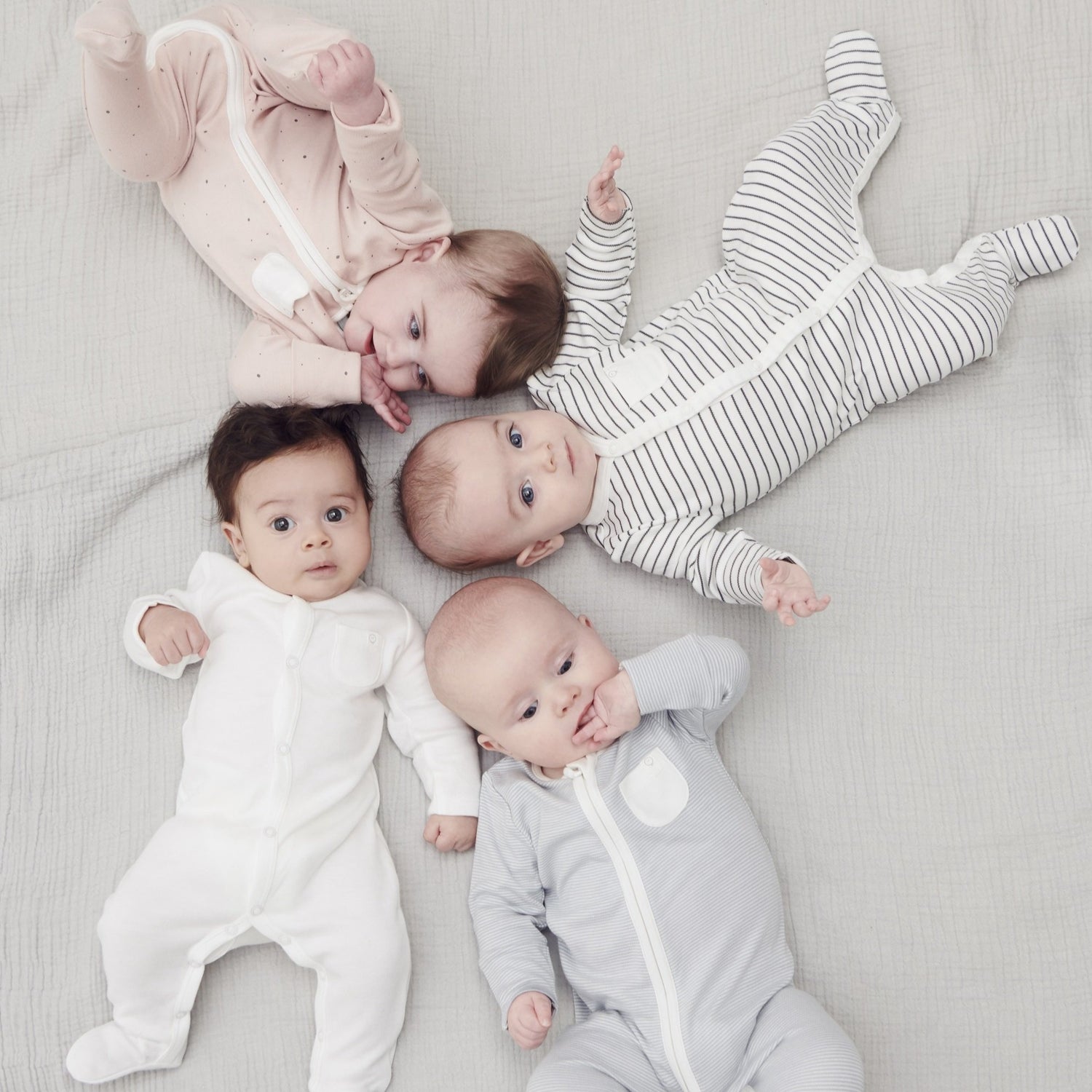 Group of babies wearing organic baby sleepsuits
