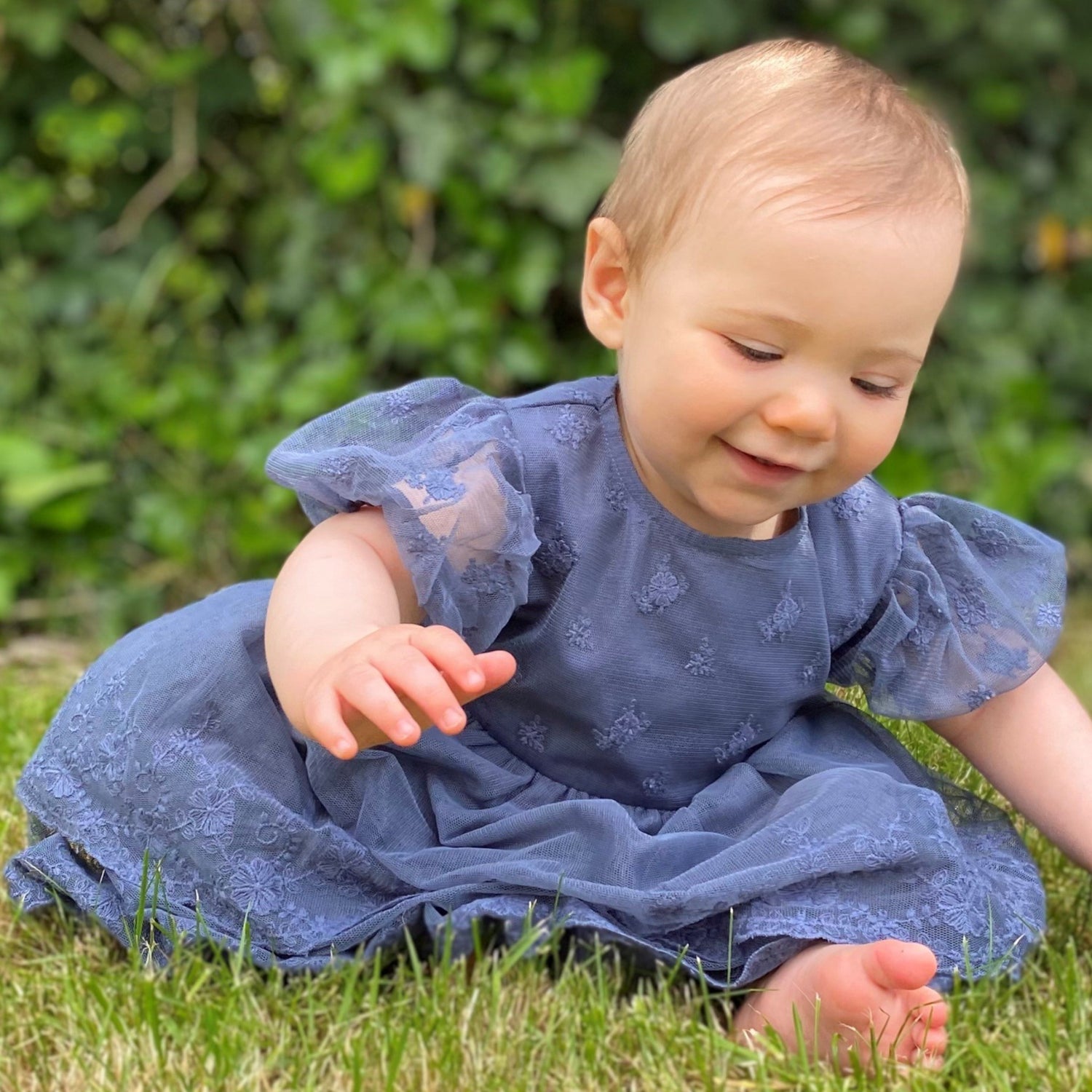 Baby wearing blue lace dress in garden