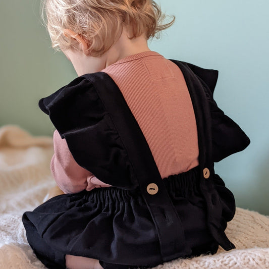 Baby wearing black pinafore dress