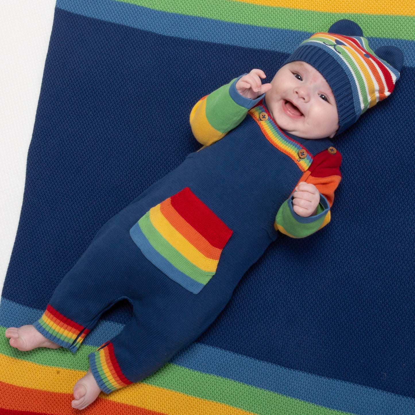Baby wearing rainbow knit dungarees