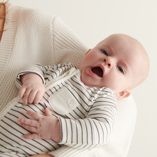 Baby yawning with grey stripe sleepsuit