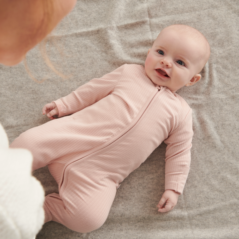 Baby wearing blush ribbed zip up sleepsuit