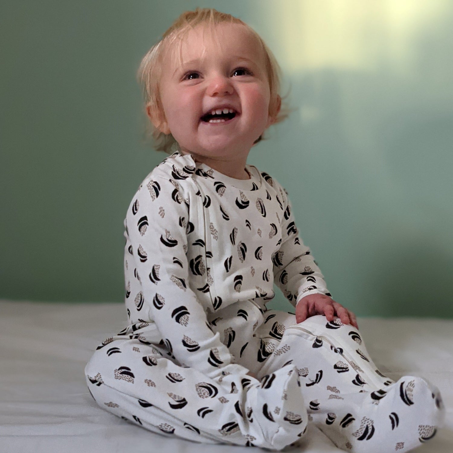 Baby smiling with wild print sleepsuit